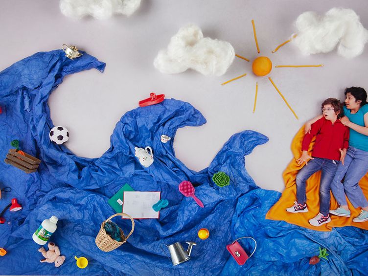 Zwei Kinder liegen auf dem Boden, aus verschiedenen, farbigen Planen wurde ein Meer mit Wellen und Strand gebildet